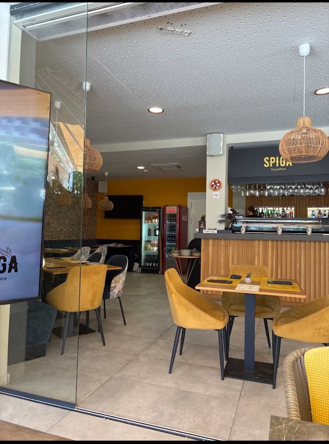 Warm candlelit interior of Spiga Calvià with teal banquettes and mustard pendant lights